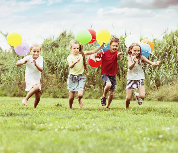 istock Four laughing kids running on green lawn 805072676