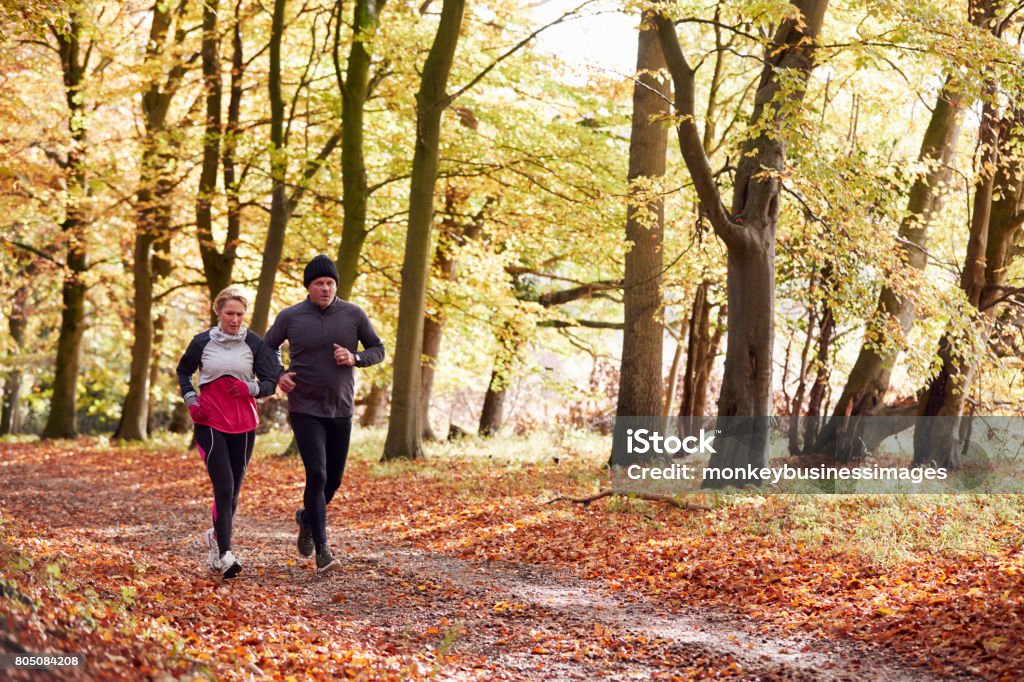 Mature Couple Running Through Autumn Woodland Together Autumn Stock Photo