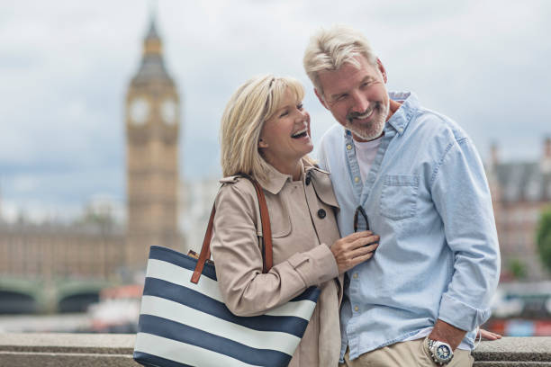 Smiling couple standing against Big Ben Happy man and woman are against Big Ben. Smiling mature couple is standing in city. They are wearing casuals. older woman purse stock pictures, royalty-free photos & images