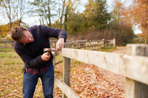 istock Mature Man Hammering Nail Into Repaired Fence 805088534
