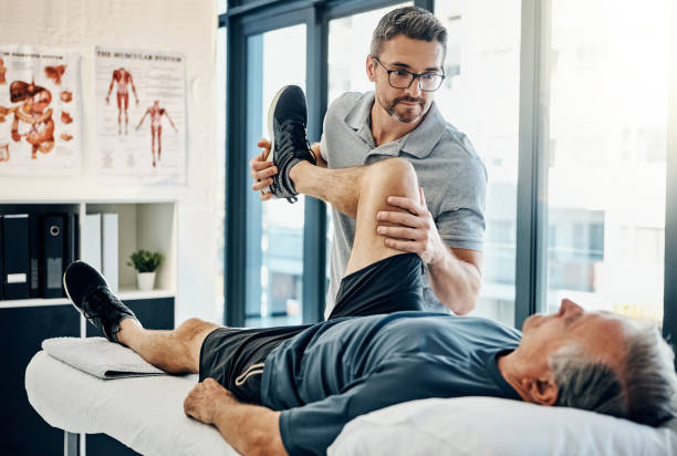 Just relax, I'll take care of the rest Shot of a friendly physiotherapist treating his mature patient in a rehabilitation center physical therapist photos stock pictures, royalty-free photos & images