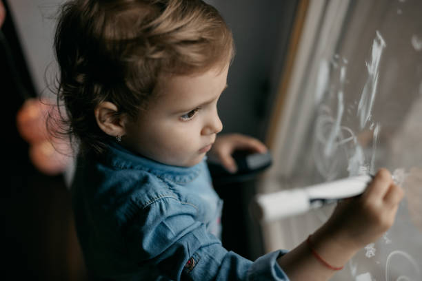 istock A lovely child is drawing on the window 805090234
