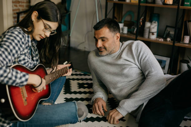 istock Teenage daugter playing guitar for her father 805095342