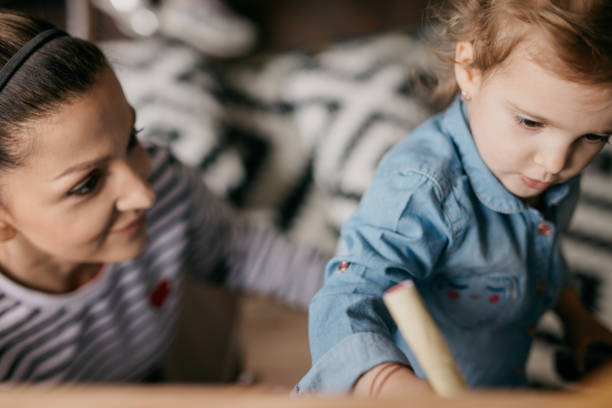 istock Mother wathing her lovely daughter draw objects on the board 805104984
