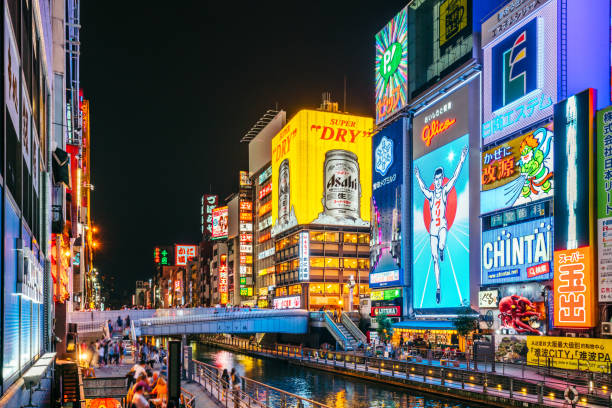 Dotonbori Canal, Osaka, Japan Tourists and locals walk below the famed advertisements lining Dotonbori Canal at. The district is one of Osaka's primary tourist destinations. japan sign stock pictures, royalty-free photos & images