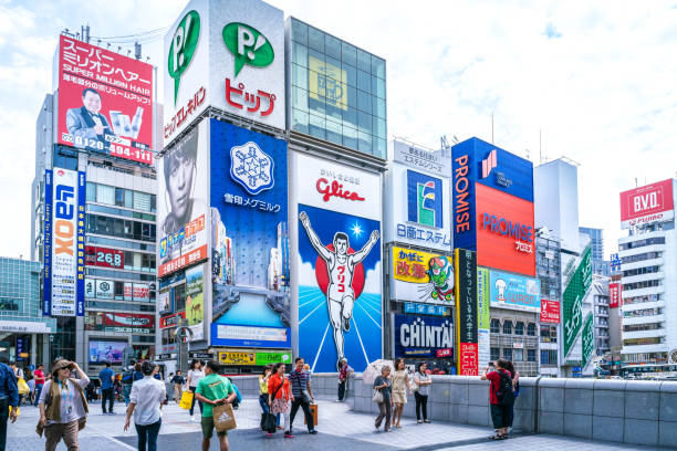 Dotonbori district, Osaka, Japan Tourists and locals walk below the famed advertisements lining Dotonbori Canal at. The district is one of Osaka's primary tourist destinations. osaka city photos stock pictures, royalty-free photos & images