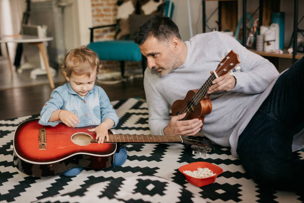 istock Baby girl is amusing her father how she plays a guitar 805109206