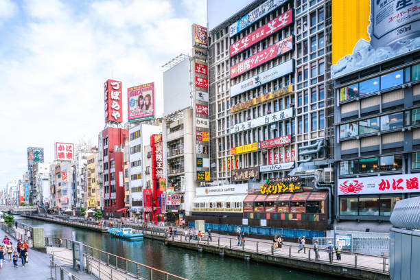 Tourists and locals walk below the famed advertisements lining Dotonbori Canal at. The district is one of Osaka's primary tourist destinations.