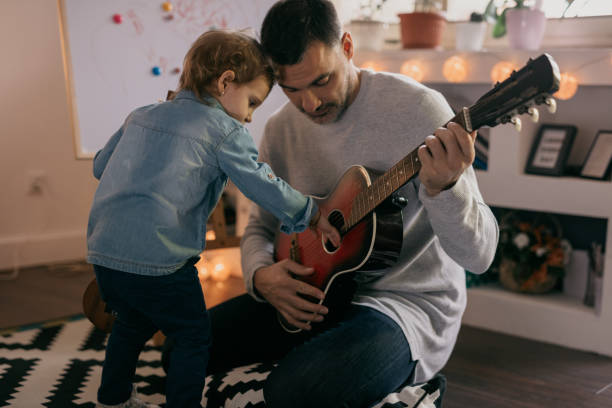 istock Cute kid triggers the stings on his father's guitar 805113772