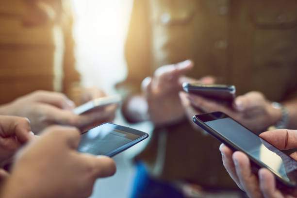 Staying connected = staying current Cropped shot of a group of colleagues using their smart phones in synchronicity people sharing photos stock pictures, royalty-free photos & images