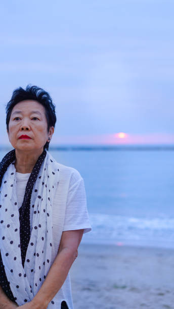 istock Asian senior standing alone and thinking at mornign beach sunrise 805125060