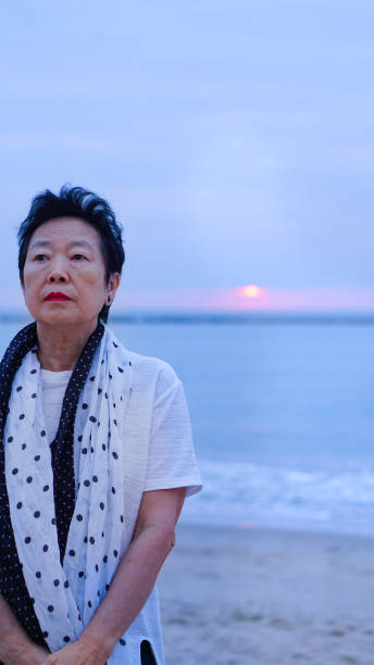 istock Asian senior standing alone and thinking at mornign beach sunrise 805125096