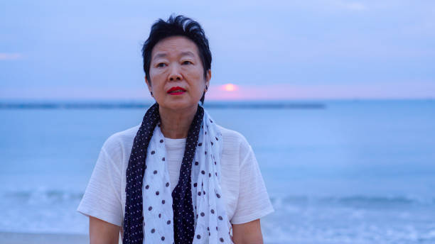 istock Asian senior standing alone and thinking at mornign beach sunrise 805125126