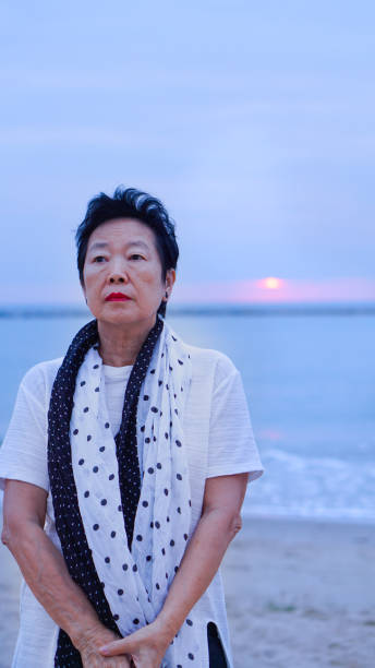 istock Asian senior standing alone and thinking at mornign beach sunrise 805125138
