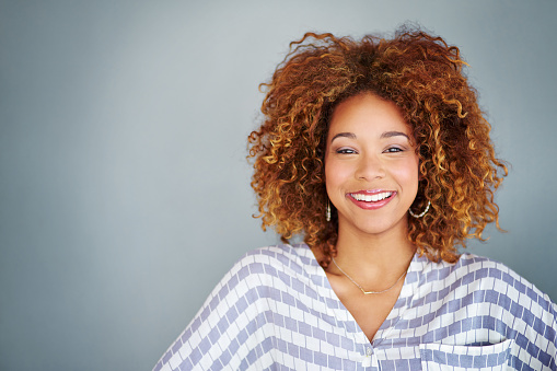 Closeup of a beautiful young woman posing against a grey background