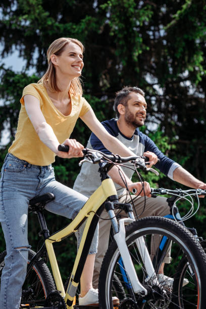 istock young smiling couple riding bicycles together at park 805170946