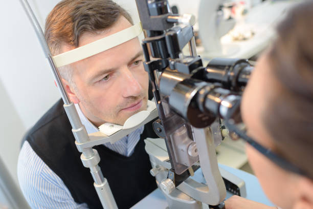 istock optometrist in exam room with man in chair 805225112