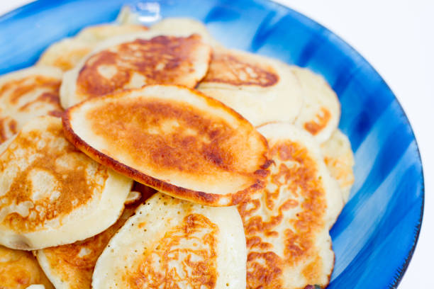 istock Ruddy freshly cooked pancakes lie on a blue plate on a white background. 805259332