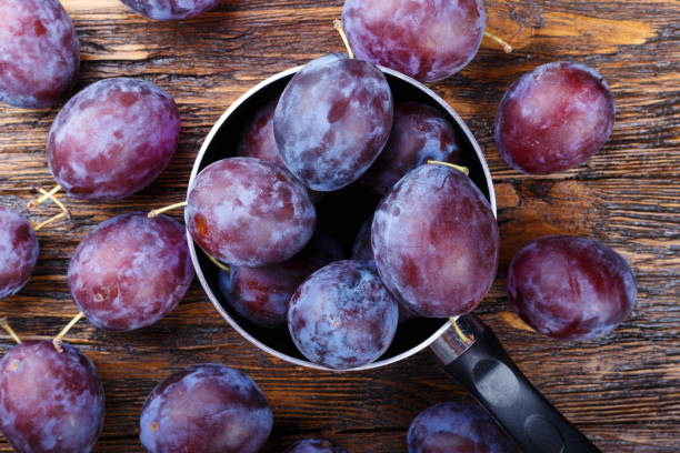 istock Ripe plums on a brown wooden table 805291764