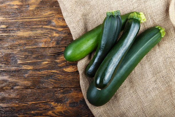Whole zucchini on a wooden background Whole zucchini  on a dark brown wooden background, space for text phallus shaped stock pictures, royalty-free photos & images