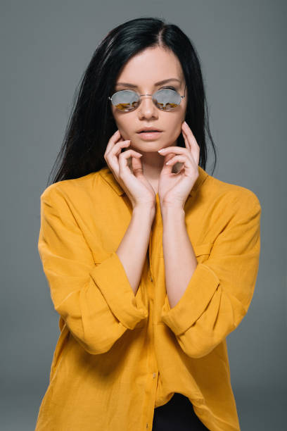 istock attractive brunette model posing in yellow blouse and sunglasses, isolated on grey 805307988