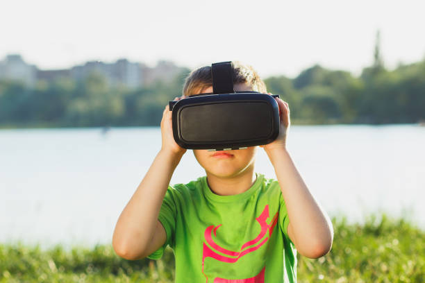 istock Boy plays game with virtual reality glasses outdoors 805377926