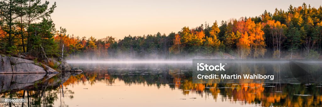 Calm lake in the forest Swedish lake in autumn colors. Early morning lake with a little fog or mist still left. Autumn Stock Photo