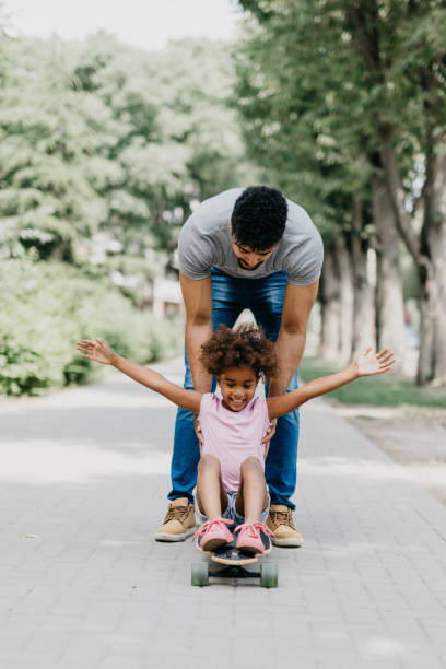 istock Father pushing his daughter on the longboard 805401838