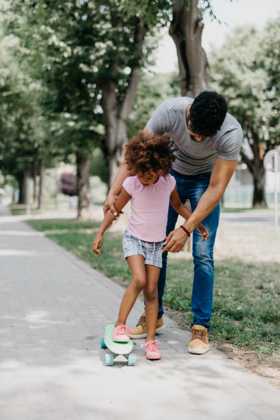 istock Single father teaches his daughter how to ride a penny board 805427736