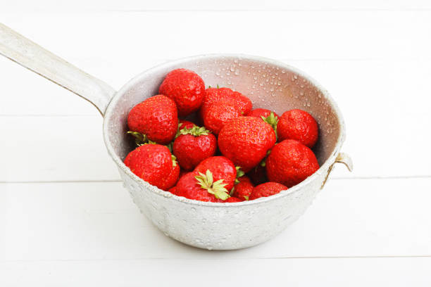 istock Ripe strawberries in an old colander on white wooden table 805466962