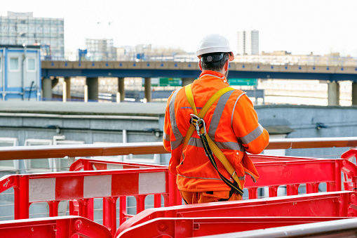 London, UK - June 25, 2017 - Back view of a construction worker walking into a building site in Canary Wharf