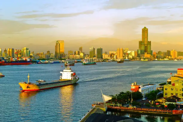 Kaohsiung Harbor at sunset with ferries/ cargo ships passing through in Kaohsiung, Taiwan.
