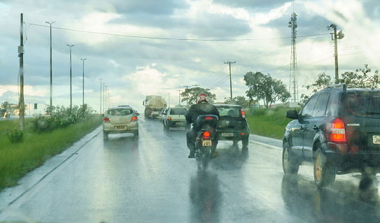 Brasilia, Brazil - March 10, 2017: Brasilia downtown traffic and motorcyclist moving in heavy rain