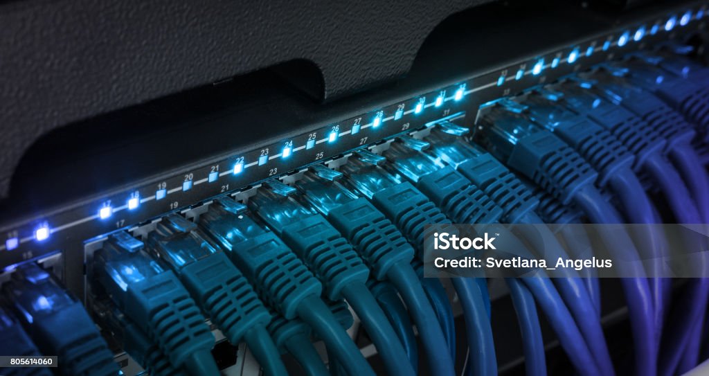 Network server panel, switch and patch cord cable in data center Network server panel, switch and patch cord cable in data center glowing in the dark. Blue led Network Connection Plug Stock Photo