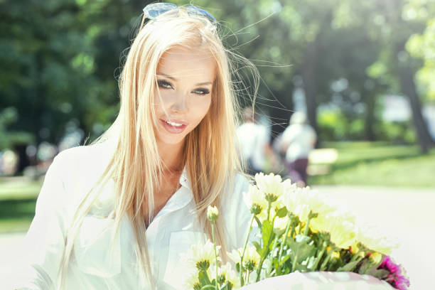 pretty woman with white wildflowers in a field near trees. High quality photo