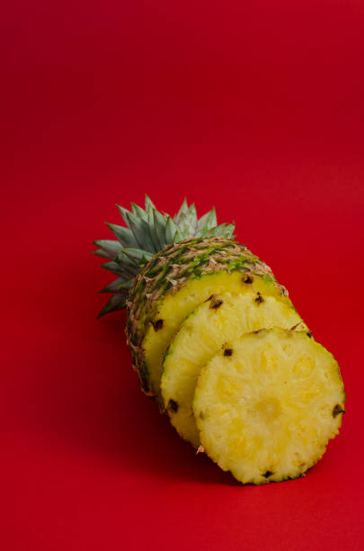 sliced pineapple fruit on red background stock photo