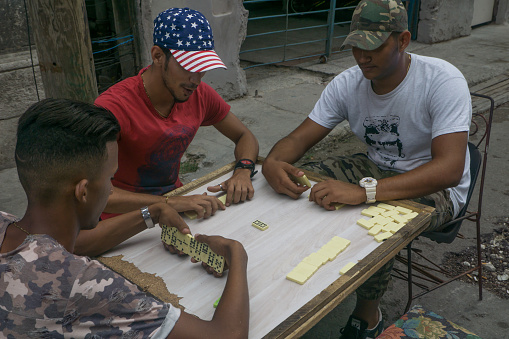 Havana, Cuba, May 14, 2017:  Three men playing dominoes game on the neighborhood street