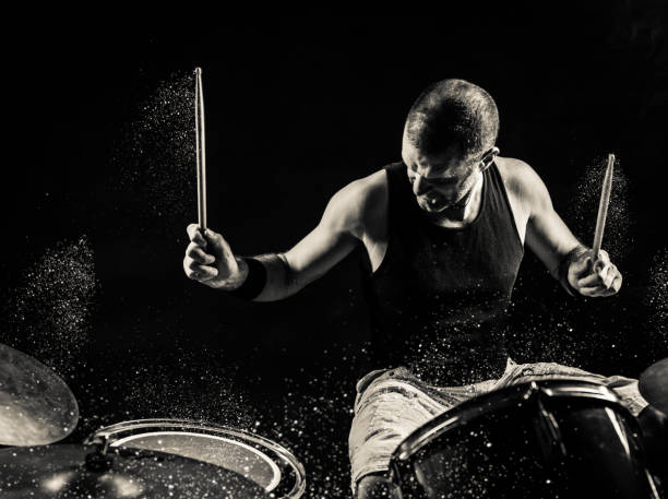 Black and White Rock N Roll Drummer A black and white image of a man playing drums on stage with glitter sparkles exploding off the drums. drummer stock pictures, royalty-free photos & images