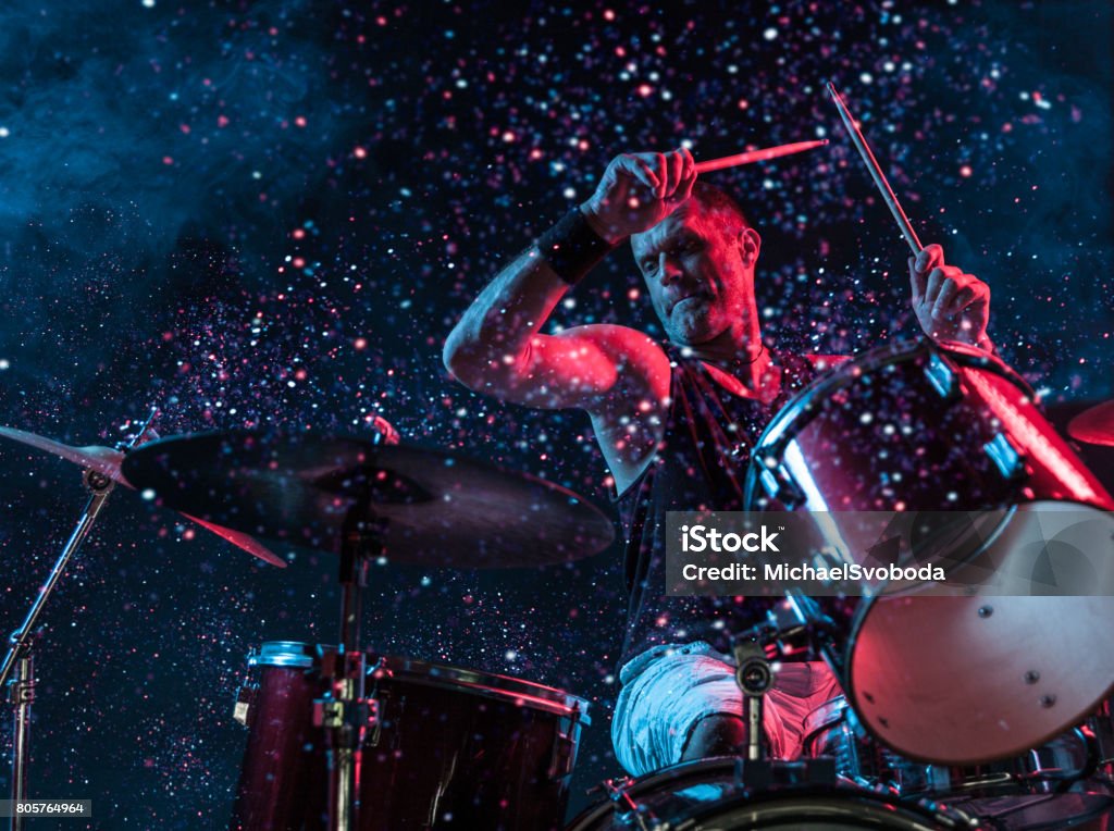 Rock N Roll Drummer Sparkles In The Air A man playing drums on stage with sparkles exploding off the drums. Rock Music Stock Photo