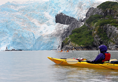 single and double kayaks near face of glacier during rainstorm, Blackstone Bay, Alaska