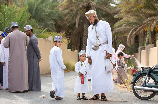 Nizwa, Oman - June 26th 2017: family in traditional clothing at a toy market on a day of Eid al Fitr, celebration at the end of Holy Month of Ramadan