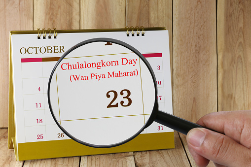 Magnifying glass in hand on calendar you can look Twenty-three days of October,Commemorates the passing of King Chulalongkorn in 1910 Every year on date 23 October is a holiday and memorial Day in Thailand.