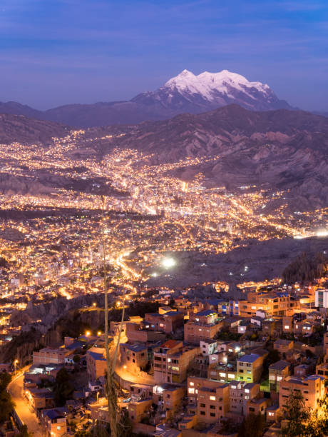 View over illuminated city La Paz, Bolivia with snow capped mountain illimani in the background at dusk evening night stock photo