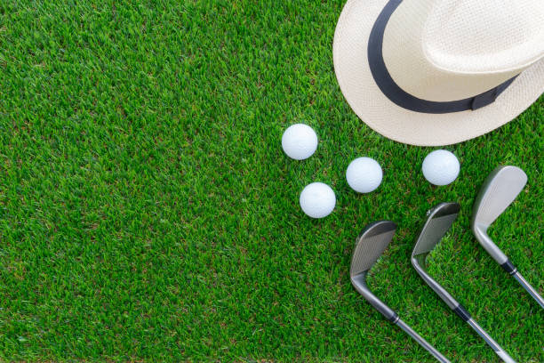 Golf concept : Panama hat, golf balls, golf iron clubs flat lay on green glass, with copy space. stock photo