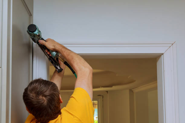 istock Carpenter brad using nail gun to moldings on doors, framing trim, 805955088
