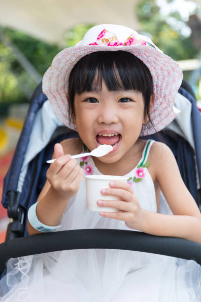 Asian Chinese little girl eating ice cream Asian Chinese little girl eating ice cream at outdoor park asian little chinese girls eating ice cream stock pictures, royalty-free photos & images