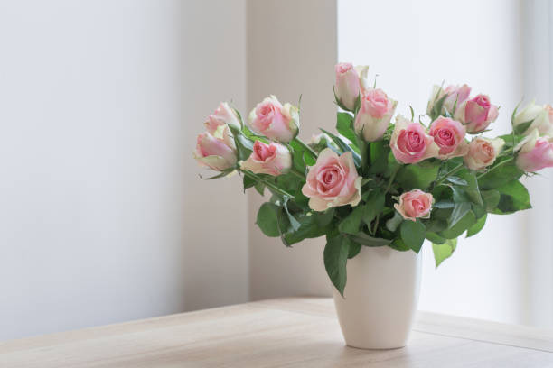 istock pink roses in vase on white background 806047164