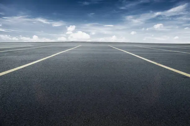 Photo of parking lot with black asphalt under blue sky