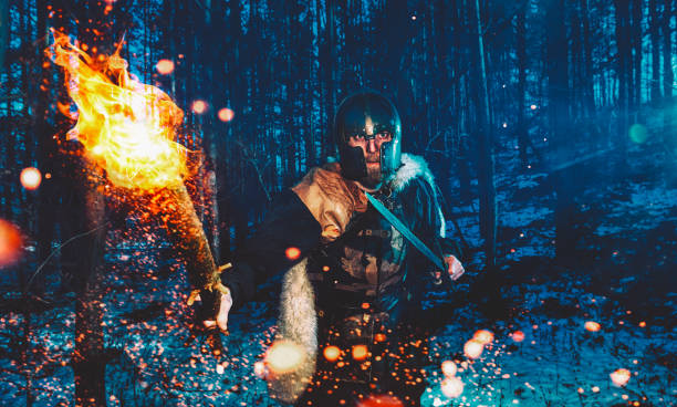 Warrior with flaming torch walks through forest at nigth ready to attack