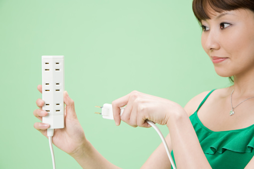 A young woman inserts a plug into a socket. A young woman plugs a charger or electrical appliance power cord into a socket. High quality photo.